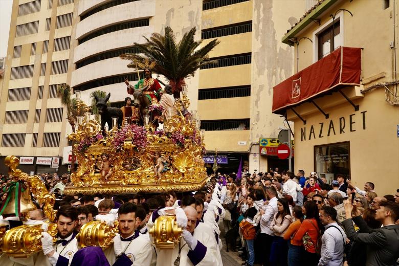 Las tradicionales palmas acompañan a Nuestro Padre Jesús a su Entrada en Jerusalén, María Santísima del Amparo y San Juan Evangelista, en la salida procesional de la Cofradía de la Pollinica de Málaga.