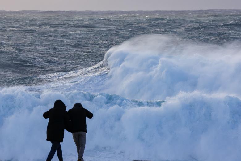 Dos turistas observan el oleaje en la costa de Muxía, este pasado miércoles en La  Coruña. Los días festivos de Semana Santa han estado dominados por la borrasca Nelson que va a dejar fuertes rachas de viento, nieve, mal estado de la mar y sobre todo lluvias en casi toda la península