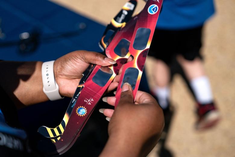 WASHINGTON, DC - APRIL 8:Volunteers hand out eclipse glasses as people gather on the National Mall to view the partial solar eclipse on April 8, 2024 in Washington, DC. People have traveled to areas across North America that are in the "path of totality" in order to experience the eclipse today, with the next total solar eclipse that can be seen from a large part of North America won't happen until 2044.   Kent Nishimura/Getty Images/AFP (Photo by Kent Nishimura / GETTY IMAGES NORTH AMERICA / Getty Images via AFP)