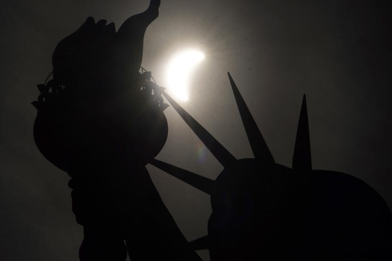 El eclipse solar cruza el cielo cerca de la corona de la Estatua de la Libertad en Liberty Island el 8 de abril de 2024, en la ciudad de Nueva York.