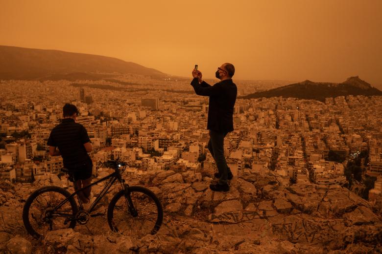 Un hombre toma una fotografía de la ciudad de Atenas desde la colina de Tourkovounia