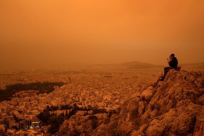 Una pareja sentada en la colina Tourkovounia, mientras los vientos del sur transportan olas de polvo sahariano, en Atenas