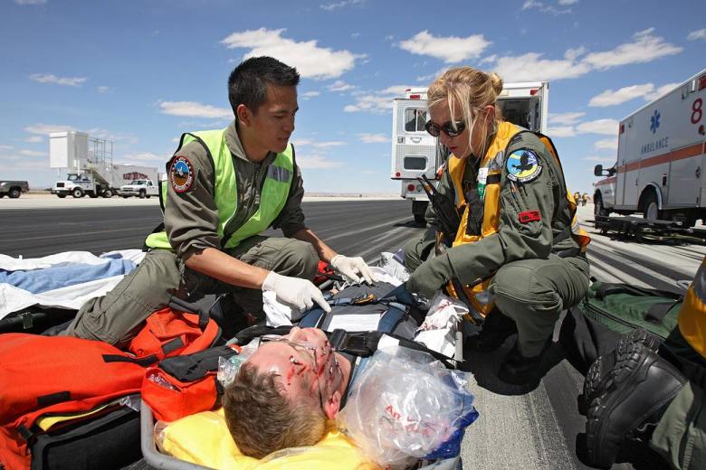 Un hombre con maquillaje para simular lesiones faciales. Un "astronauta" voluntario es atendido por personal de rescate aeromédico después de la evacuación de la maqueta del transbordador.