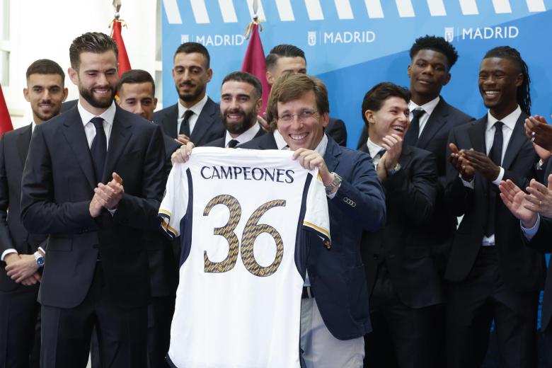 El alcalde de Madrid, José Luis Martínez-Almeida (i) recibe una camiseta del Real Madrid durante la recepción que ha tenido lugar en ayuntamiento de la capital como parte de los actos de celebración de la trigésimo sexta Liga conseguida por el equipo este domingo en Madrid. El equipo visita hoy las sedes de la Comunidad de Madrid y el Ayuntamiento para finalizar en la plaza de Cibeles y celebrar con aficionados