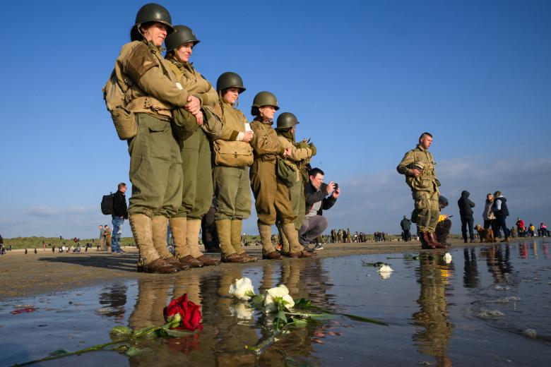 Participantes en la recreación del Día D guardan silencio tras homenajear con rosas a los caídos en el desembarco aliado en las playas de Francia durante la Segunda Guerra Mundial