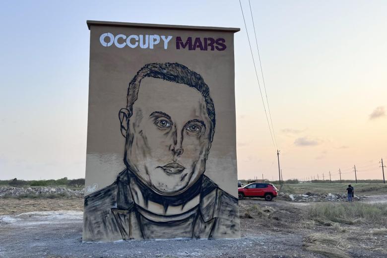 Las casitas con el césped recién cortado no difieren mucho de las de cualquier pueblo texano, pero los grandes murales con la cara de Elon Musk (como el de la imagen), nombres de calles como 'Rocket Road' y la discreción de sus habitantes los delata: está usted entrando en Starbase, "la última parada antes de llegar a Marte".