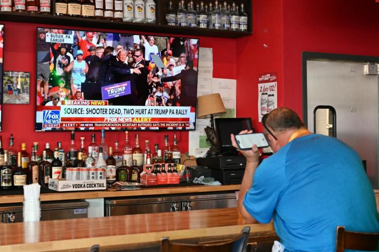 Imagen de un bar donde la televisión muestra la imagen del atentado contra Trump.