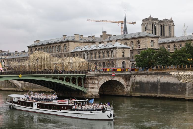 Athletes from Greece's delegation sail in a boat along the river Seine near Notre Dame de Paris cathedral during the opening ceremony of the Paris 2024 Olympic Games in Paris on July 26, 2024. (Photo by Jack GUEZ / AFP)