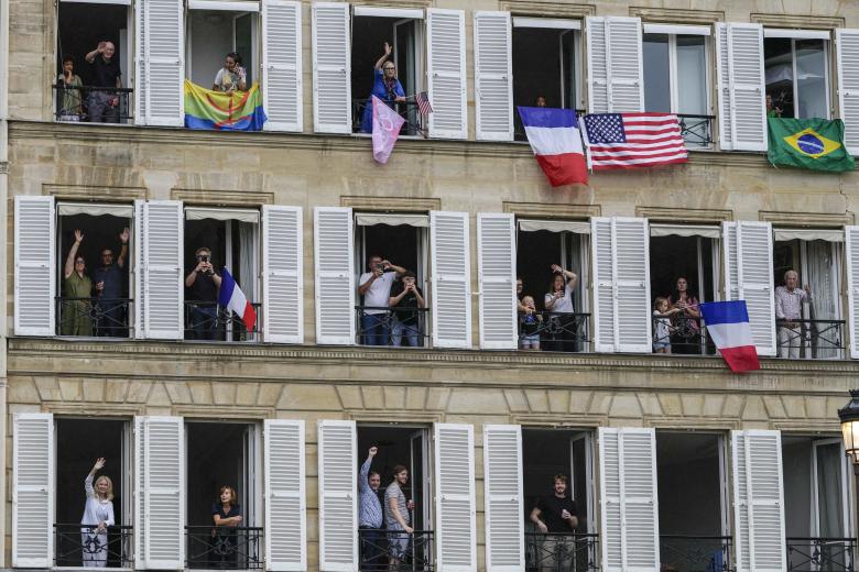 La gente saluda desde los balcones en París, Francia, durante la ceremonia de apertura de los Juegos Olímpicos