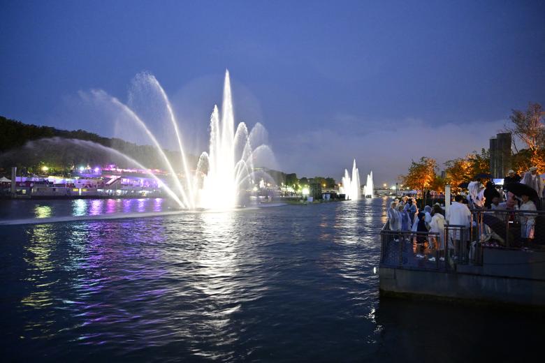 Los espectadores observan un espectáculo de luz y agua desde las orillas del río Sena durante la ceremonia de apertura de los Juegos Olímpicos de París 2024