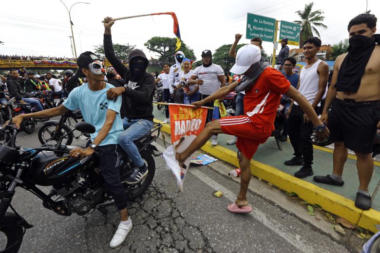 Un manifestante patea una pancarta de campaña del presidente venezolano Nicolás Maduro durante una protesta en Valencia, estado Carabobo, Venezuela