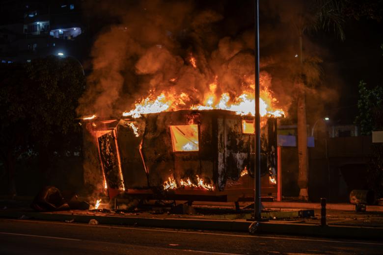 Fotografía de un módulo de la Policía Nacional Bolivariana incendiado durante las protestas por los resultados de las elecciones presidenciales este lunes, en la autopista Prados del Este, en Caracas