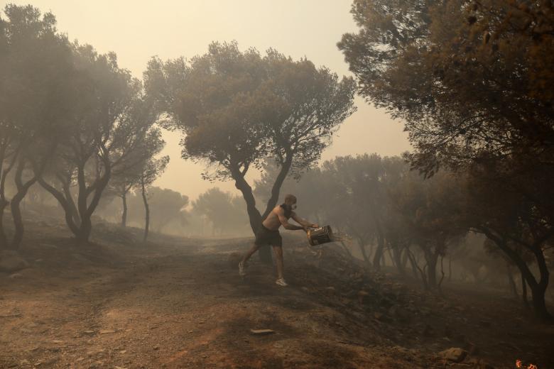 Un vecino lucha contra las llamas con un cubo de agua en Patima Halandri, un suburbio de Atenas