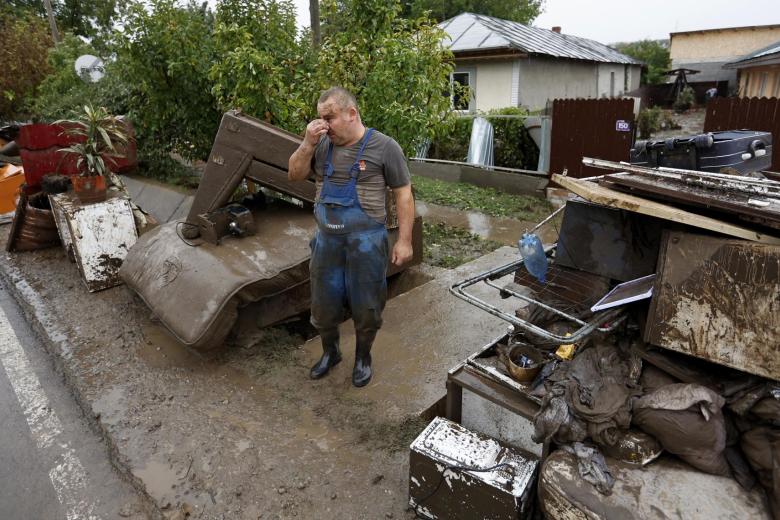 Marian, un rumano de 45 años, reacciona frente a la casa de su familia, cerca de una pila de objetos rescatados en la aldea afectada por las inundaciones de Slobozia Conachi, cerca de la ciudad de Galati, Rumania