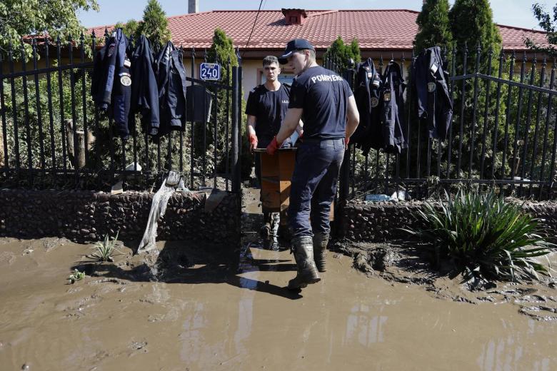 Rescatistas rumanos llevan muebles fuera de una escuela inundada en el pueblo de Pechea, afectado por las inundaciones