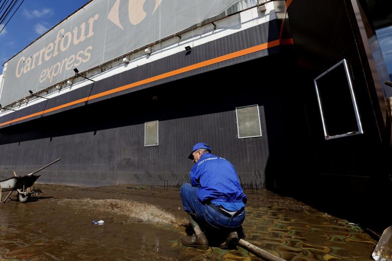 Trabajadores de un supermercado limpian los desperfectos causados por las inundaciones de la tormenta Boris