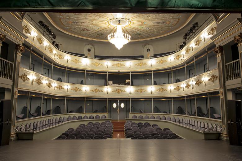 Pequeño, recogido y de una belleza inigualable. ¿Es el Real Coliseo del Escorial el teatro más bonito de España? Tal vez, y tal vez también de Europa. Construido en 1752 dentro de las reformas impulsadas por el Rey Carlos III en el Real Sitio de San Lorenzo del Escorial, que transformó el austero conjunto Habsburgo en un exuberante lugar de recreo borbónico, el Real Coliseo del Escorial es un teatro único que acoge tanto obras de teatro de Lope, Calderón o Shakespeare, como espectáculos flamencos o conciertos de música clásica.