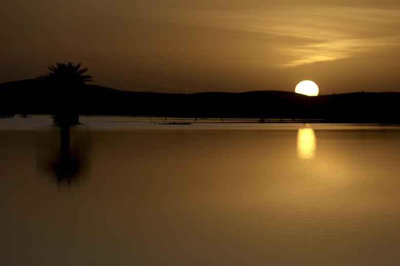 El sol se pone detrás de las dunas del lago Yasmina, un lago estacional en el pueblo de Merzouga en el desierto del Sahara