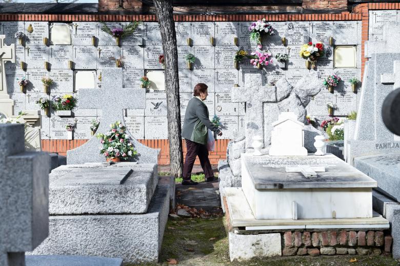 Una mujer lleva flores a un ser querido, en el Cementerio de la Almudena, Madrid