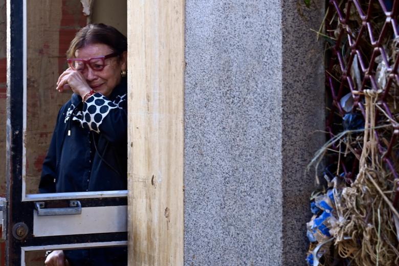 Una mujer llora en la entrada de su casa tras los devastadores efectos de las inundaciones. Decenas de familias buscan en Valencia a un número indeterminado de desaparecidos.