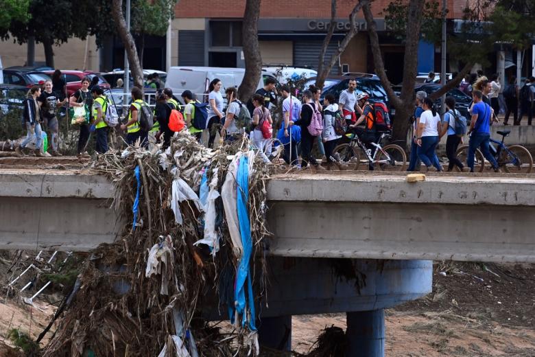 Los voluntarios cruzan un puente cuando llegan a Paiporta para ayudar con la limpieza de la localidad valenciana.