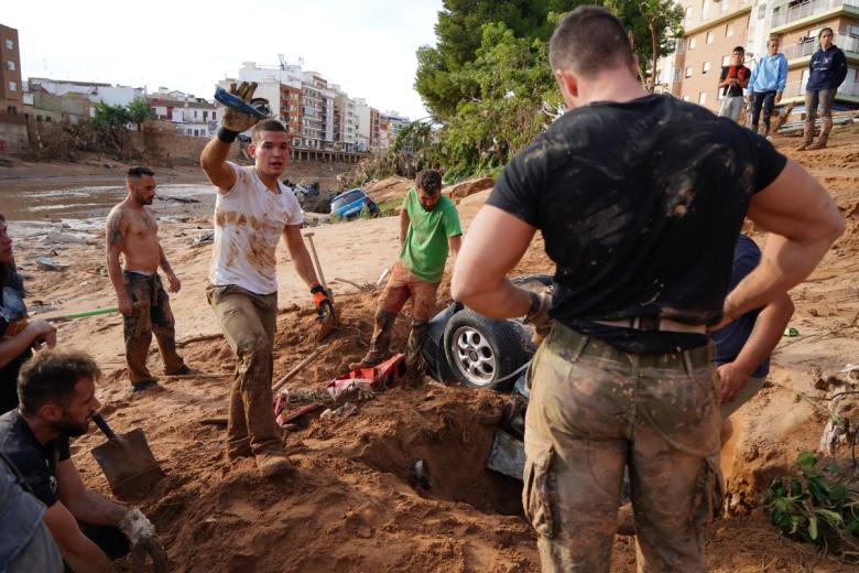 Un grupo de personas intenta desenterrar un coche en busca de víctimas. El número de desaparecidos como consecuencia de la DANA sigue siendo indeterminado