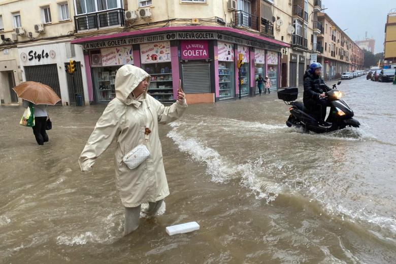 MÁLAGA, 13/11/2024.- Una persona pasa por una calle ha inundado debido a las fuertes lluvias y granizo registrado este miércoles en Málaga que están causando acumulación de grandes balsas en algunas de las principales avenidas de todos los distritos de la ciudad. EFE/Montserrat Martínez