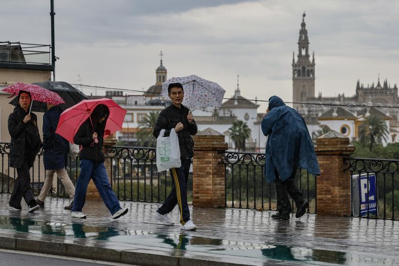 Varias personas caminan por Sevilla capital este jueves en el que la Agencia Estatal de Meteorología (Aemet) mantiene la alerta naranja por lluvias en la provincia sevillana. EFE /José Manuel Vidal