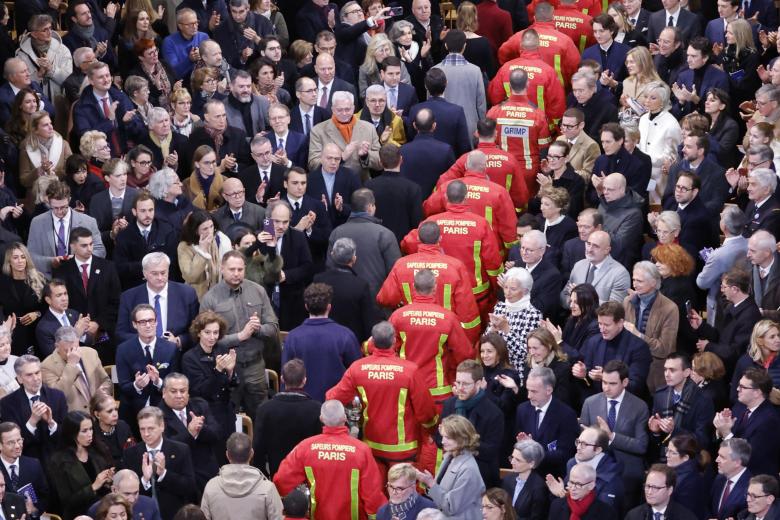 Bomberos, rescatadores y constructores, involucrados en la restauración de la catedral de Notre Dame de París, desfilan durante su ceremonia oficial de reapertura