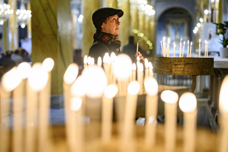 Una pareja musulmana junto a la hoguera ante el santuario de la Virgen María durante el servicio de Nochebuena en la catedral católica siríaca del Sagrado Corazón en la ciudad meridional iraquí de Basora el 24 de diciembre de 2024