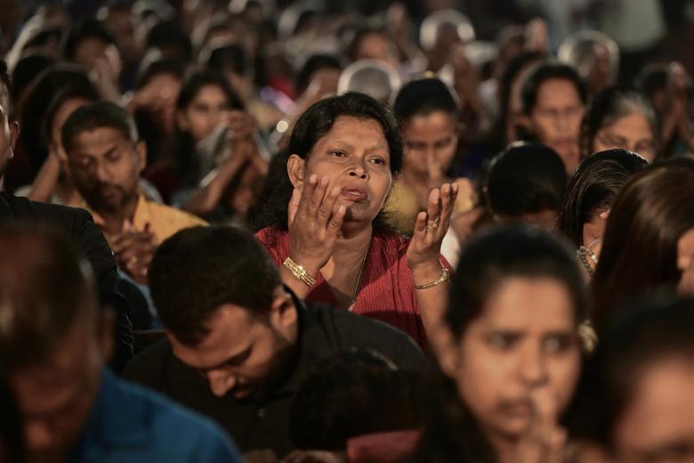 Una pareja musulmana junto a la hoguera ante el santuario de la Virgen María durante el servicio de Nochebuena en la catedral católica siríaca del Sagrado Corazón en la ciudad meridional iraquí de Basora el 24 de diciembre de 2024