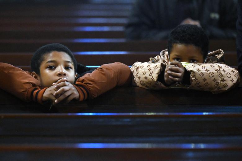 Una pareja musulmana junto a la hoguera ante el santuario de la Virgen María durante el servicio de Nochebuena en la catedral católica siríaca del Sagrado Corazón en la ciudad meridional iraquí de Basora el 24 de diciembre de 2024