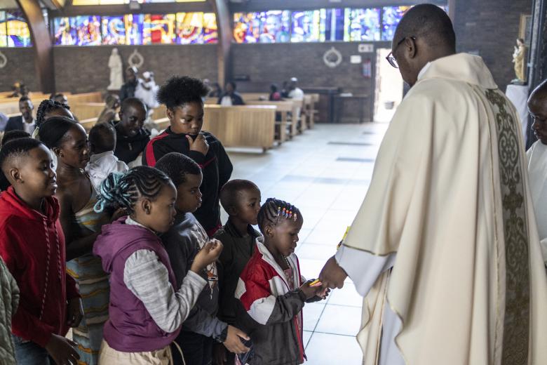 Una pareja musulmana junto a la hoguera ante el santuario de la Virgen María durante el servicio de Nochebuena en la catedral católica siríaca del Sagrado Corazón en la ciudad meridional iraquí de Basora el 24 de diciembre de 2024