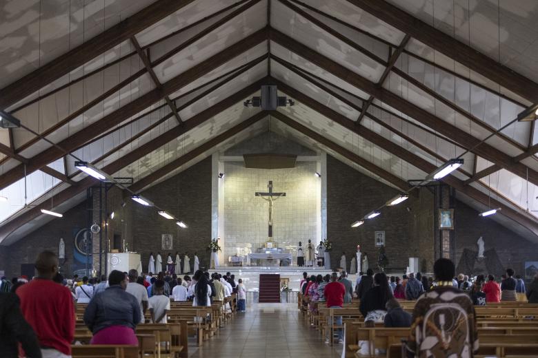 Una pareja musulmana junto a la hoguera ante el santuario de la Virgen María durante el servicio de Nochebuena en la catedral católica siríaca del Sagrado Corazón en la ciudad meridional iraquí de Basora el 24 de diciembre de 2024