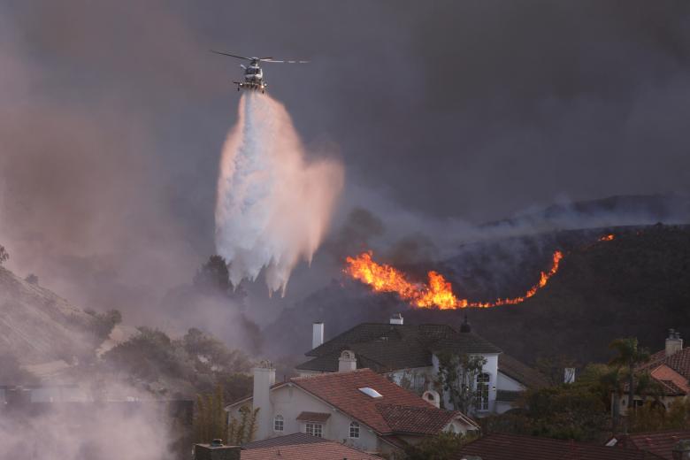 Un helicóptero arroja agua sobre las casas amenazadas por el incendio Palisades