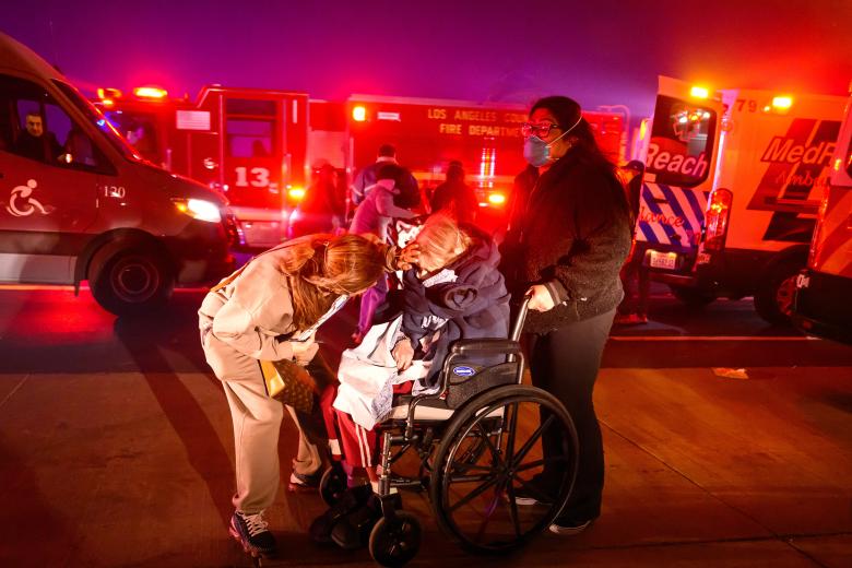 Velma Wright, de 102 años, es evacuada de un centro de atención mientras se acercan brasas y llamas durante el incendio de Eaton en Pasadena