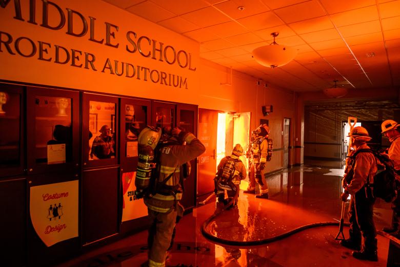 Los bomberos se preparan para combatir las llamas desde el interior del auditorio de la escuela secundaria Eliot Arts Magnet mientras la escuela se quema durante el incendio de Eaton