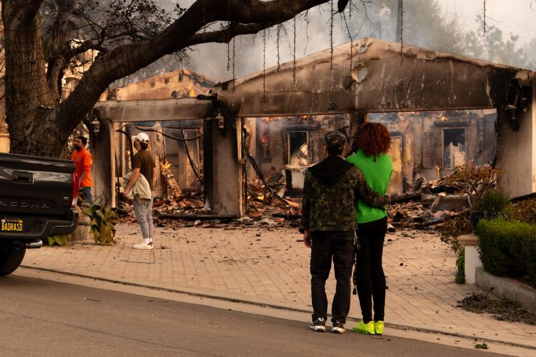 Personas observan una casa afectada por un incendio este miércoles, en Altadena