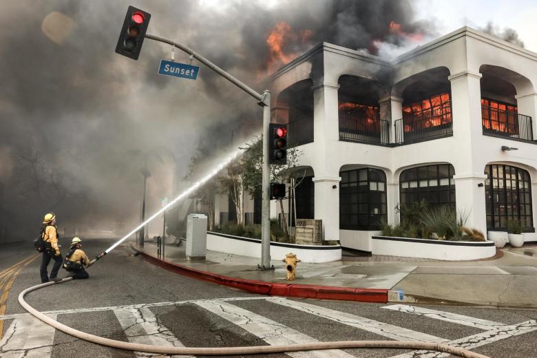 Los bomberos luchan contra las llamas que envuelven un edificio durante el incendio forestal de Palisades en el vecindario Pacific Palisades de Los Ángeles.