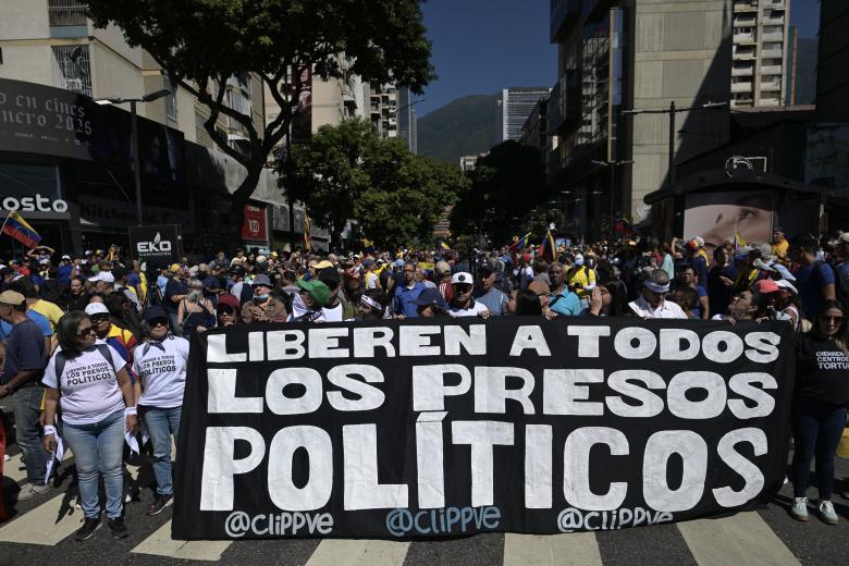 Los manifestantes sostienen una pancarta exigiendo la liberación de todos los presos políticos durante una protesta convocada por la oposición en vísperas de la toma de posesión presidencial, en Caracas