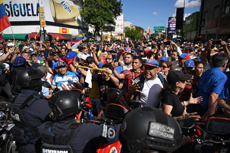 Manifestantes bloquean a miembros de la policía después de que la líder opositora venezolana María Corina Machado pronunciara un discurso durante la protesta convocada por la oposición en Caracas