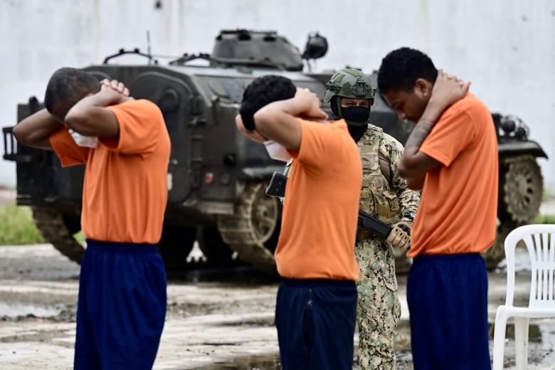 Military personnel walk past inmates during a tour to check the reinforcement of security in the wards in order to prevent riots, at the Penitenciaria del Litoral in Guayaquil, Ecuador, on April 9, 2025. (Photo by MARCOS PIN / AFP)
