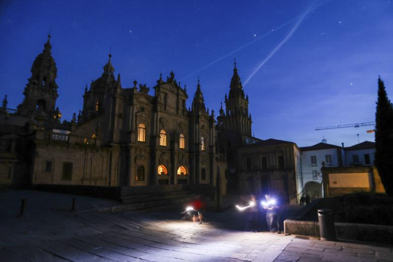 Unos turistas pasan con linternas por la plaza de Azabachería de Santiago de Compostela durante esta pasada noche del apagón eléctrico. EFE/Xoán Rey