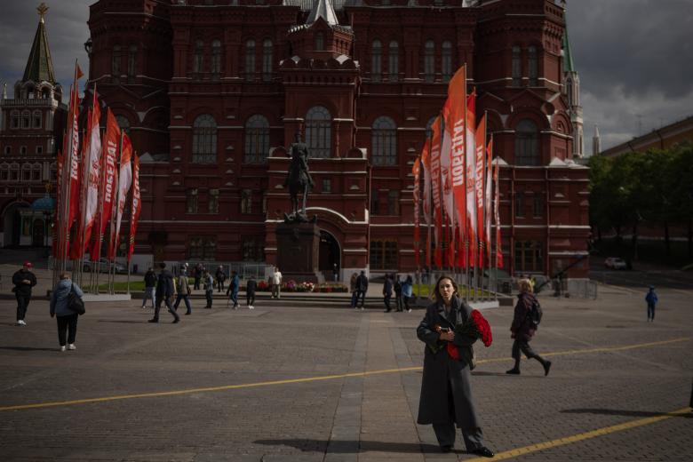 Una mujer con claveles rojos se encuentra en la céntrica plaza Manezhnaya, decorada para las celebraciones del Día de la Victoria
