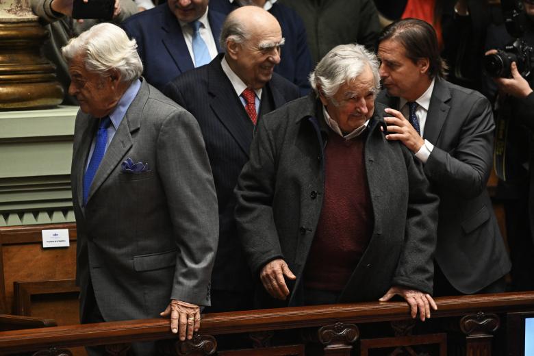 Uruguayan former President Jose Mujica (L) is honored by Alessandro Preti (R), chief of reintegration of the UN Verification Mission in Colombia, for his contribution to the Colombian peace process in Montevideo on February 16, 2023. (Photo by Pablo PORCIUNCULA / AFP)