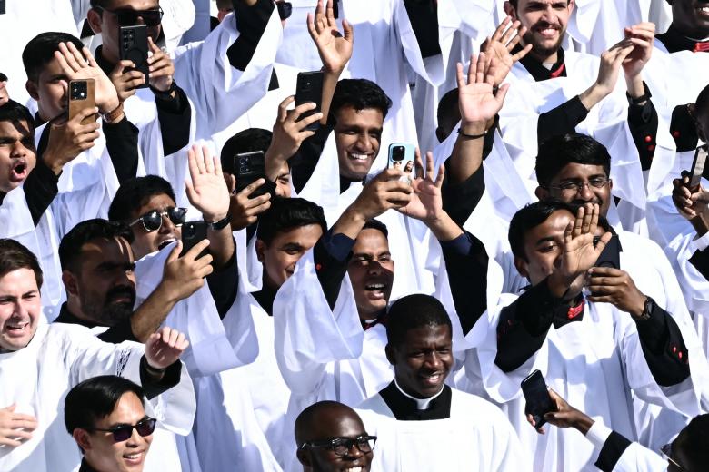 Los sacerdotes saludan mientras el Papa León XIV saluda a la multitud desde el papamóvil antes de la Santa Misa de inicio de su pontificado