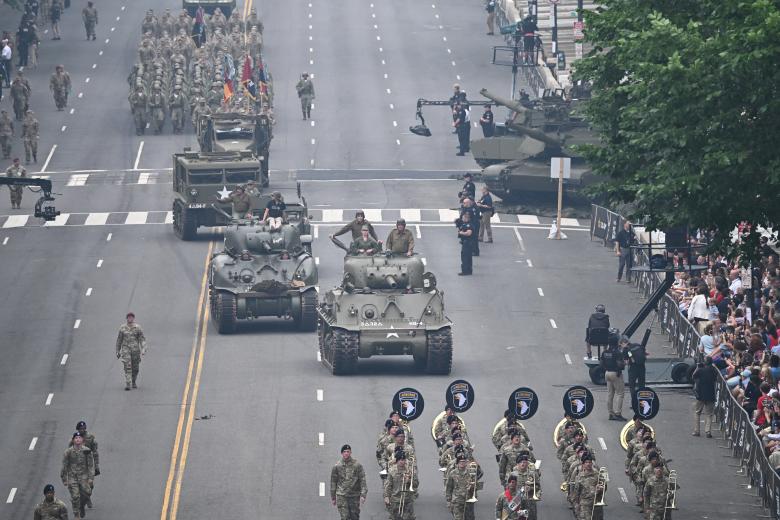 US President Donald Trump stands and salutes troops during the Army 250th Anniversary Parade in Washington, DC on June 14, 2025. Trump's long-held dream of a parade will come true as nearly 7,000 troops plus dozens of tanks and helicopters rumble through the capital in an event officially marking the 250th anniversary of the US army. (Photo by Doug MILLS / POOL / AFP)