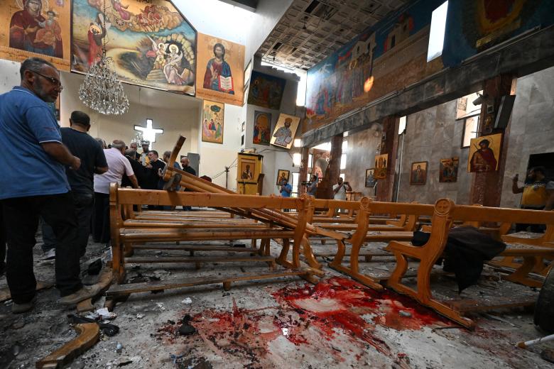 Un hombre observa manchas de sangre mientras los rescatistas inspeccionan los daños