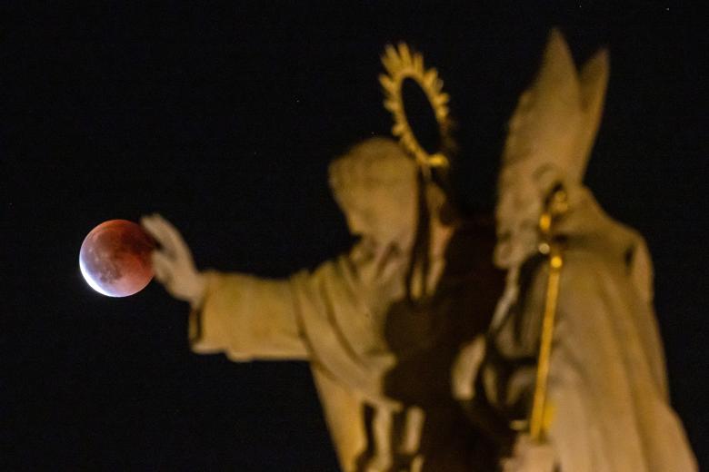 La 'Luna de Sangre' se observa durante un eclipse total sobre el centro de Praga este domingo, en República Checa. Los eclipses lunares, opuestos a los eclipses solares, ocurren cuando la Tierra se interpone entre la Luna llena y el Sol.