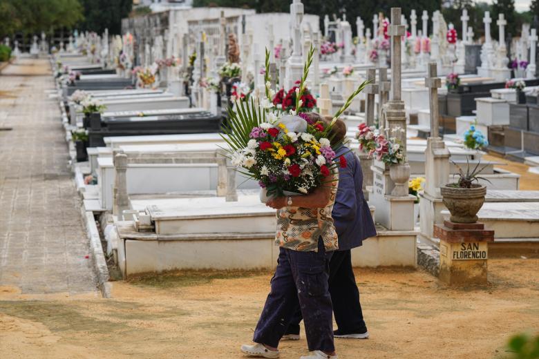 Dos personas llevan flores a un ser querido en el Cementerio de San Fernando, Sevilla